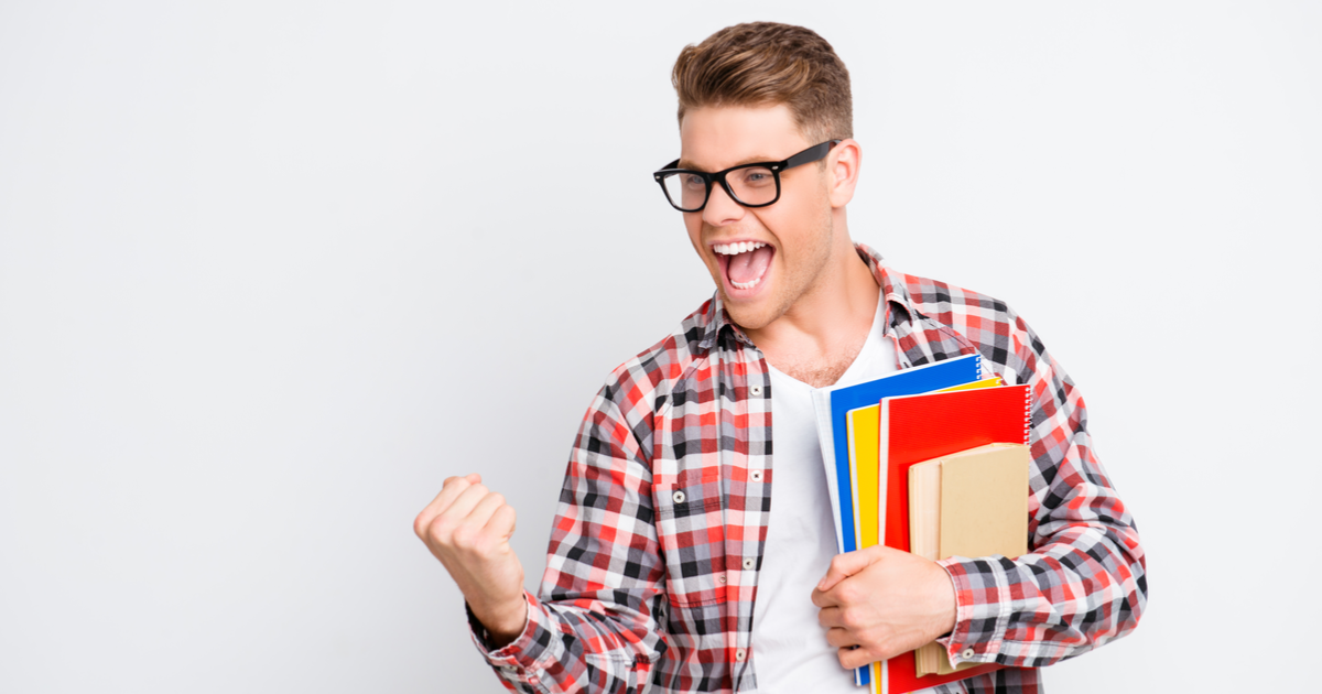 счастливый студент показывает зачетку на фоне университета